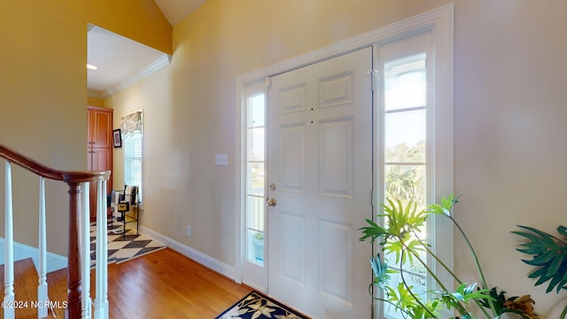 foyer entrance with baseboards, crown molding, stairway, and light wood-style floors