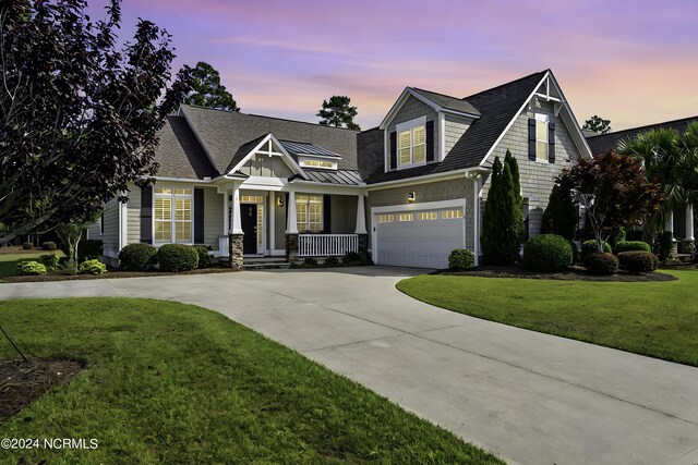 view of front of house featuring covered porch, a yard, and a garage