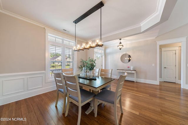 dining space with a decorative wall, a wainscoted wall, wood finished floors, visible vents, and crown molding