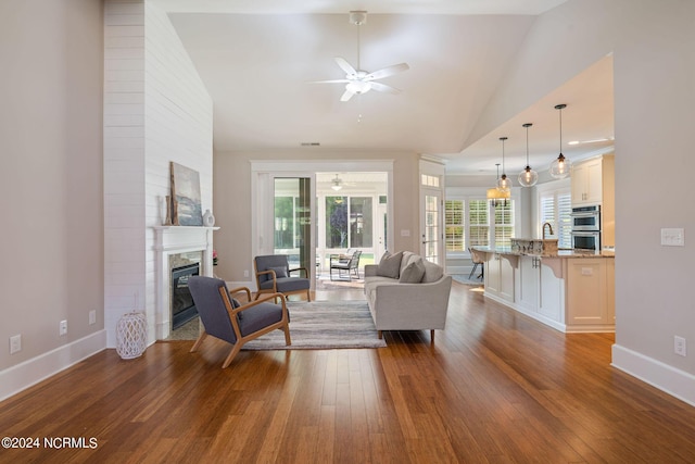 living room featuring wood-type flooring, a ceiling fan, a glass covered fireplace, high vaulted ceiling, and baseboards