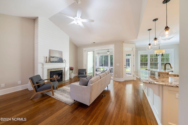 living room featuring a fireplace with flush hearth, dark wood finished floors, lofted ceiling, and a healthy amount of sunlight