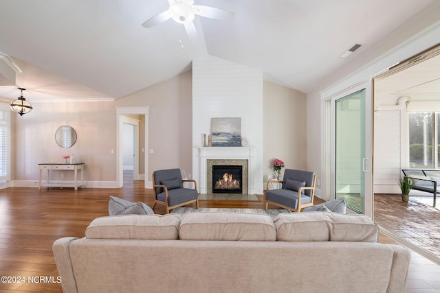 living room featuring lofted ceiling, a fireplace with flush hearth, wood finished floors, visible vents, and baseboards