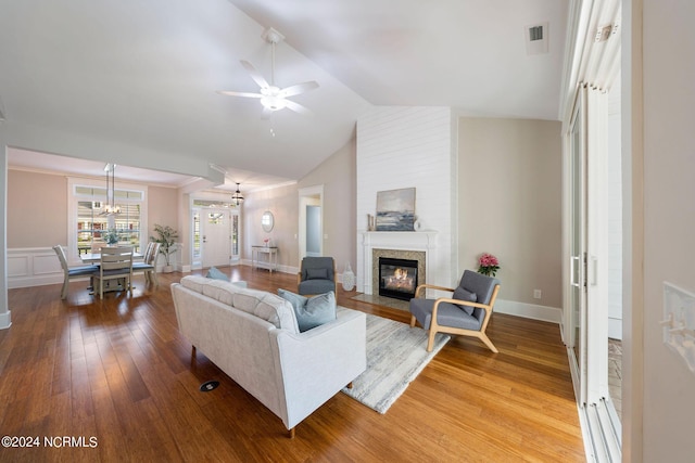 living room with hardwood / wood-style flooring, a fireplace with flush hearth, visible vents, a ceiling fan, and vaulted ceiling