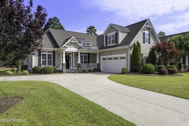 view of front of house featuring covered porch, a garage, and a front yard