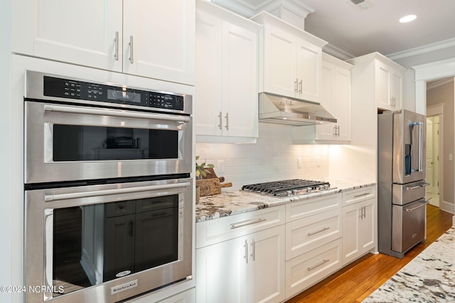 kitchen with white cabinets, under cabinet range hood, ornamental molding, and stainless steel appliances