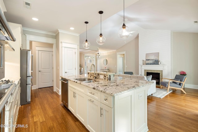 kitchen with a fireplace, visible vents, freestanding refrigerator, a sink, and wood finished floors