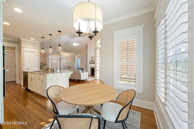 dining area featuring ornamental molding, a fireplace, dark wood finished floors, and baseboards