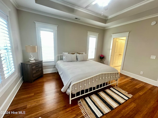 bedroom with baseboards, a raised ceiling, wood finished floors, and ornamental molding