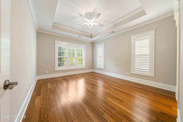 unfurnished room featuring ceiling fan, a tray ceiling, hardwood / wood-style flooring, and baseboards