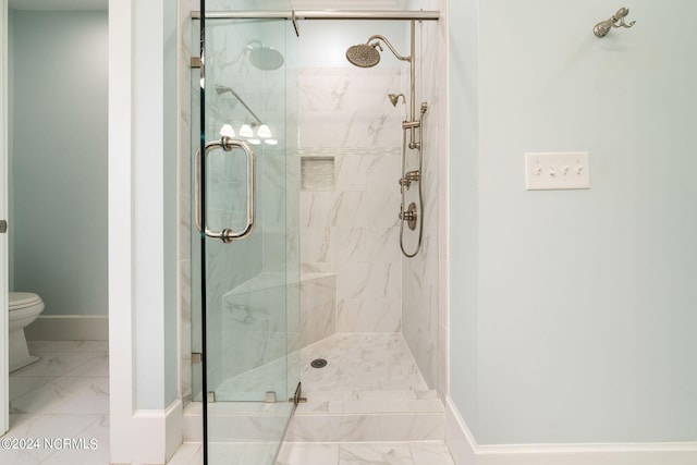 full bathroom featuring a stall shower, marble finish floor, baseboards, and toilet