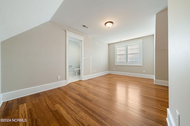 additional living space with lofted ceiling, visible vents, baseboards, and wood finished floors