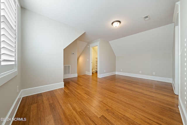 additional living space with light wood finished floors, visible vents, and baseboards