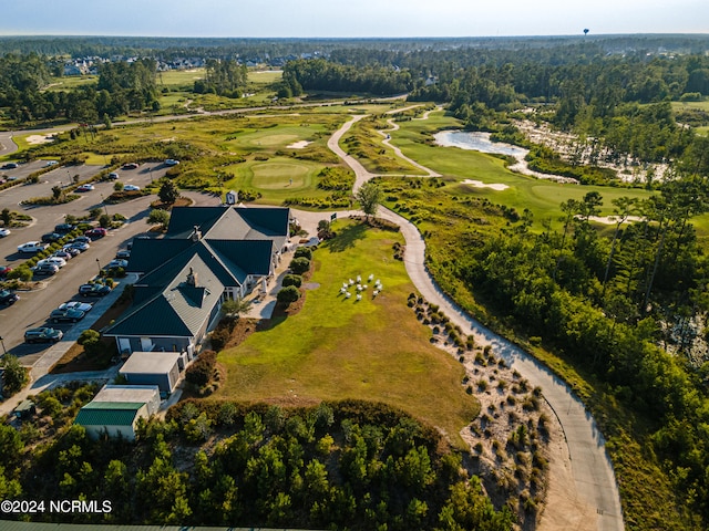 drone / aerial view with view of golf course and a wooded view