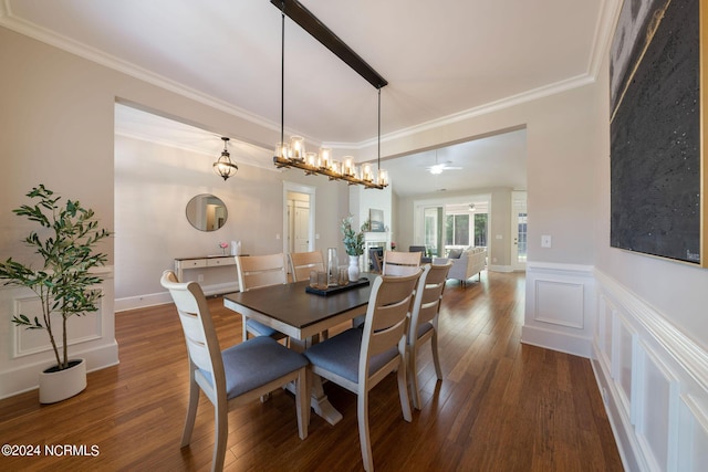 dining space featuring dark wood-style floors, ornamental molding, a decorative wall, and wainscoting