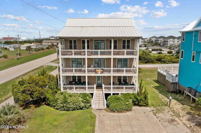 back of property featuring a balcony and a lawn