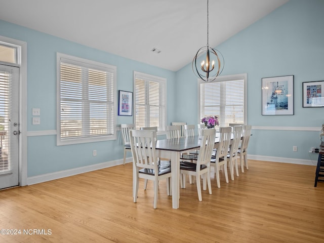 dining area with vaulted ceiling, a chandelier, and light hardwood / wood-style floors