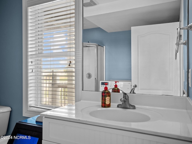 bathroom featuring vanity, toilet, and a shower with door