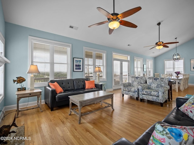 living room featuring vaulted ceiling, plenty of natural light, ceiling fan with notable chandelier, and light hardwood / wood-style floors