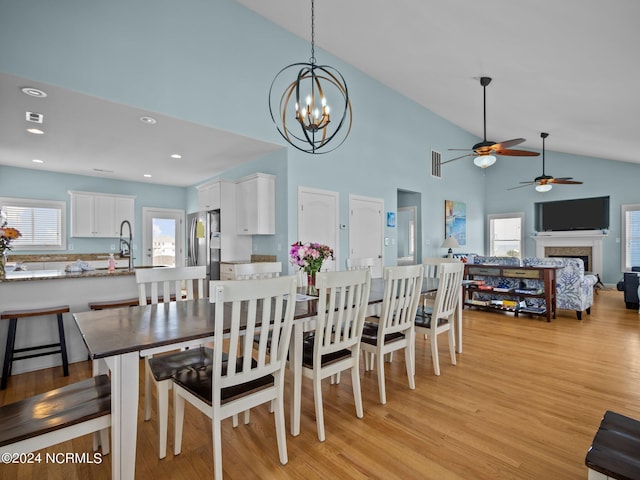 dining area with sink, an inviting chandelier, high vaulted ceiling, and light hardwood / wood-style flooring