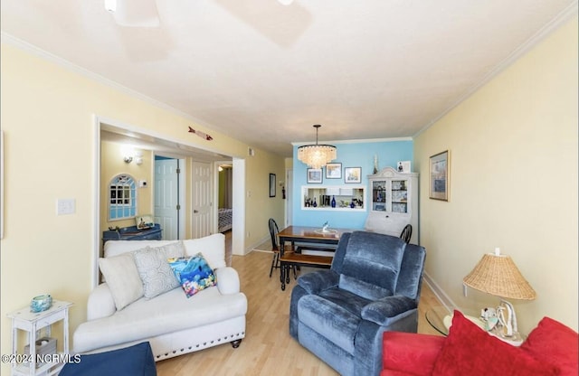 living room featuring an inviting chandelier, crown molding, and light hardwood / wood-style flooring