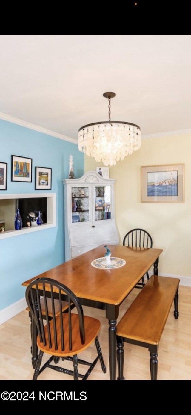 dining room featuring an inviting chandelier, ornamental molding, and light hardwood / wood-style floors