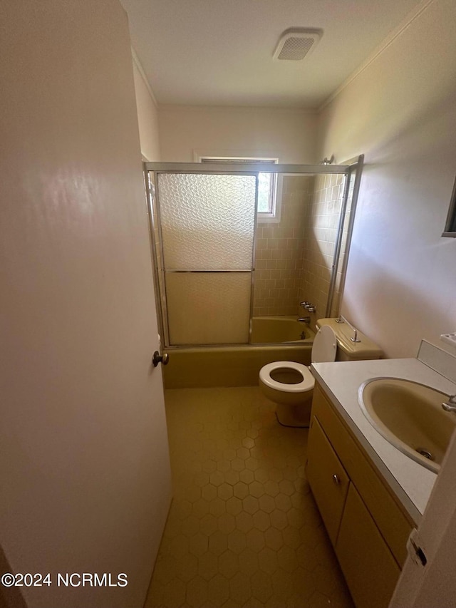 full bathroom with enclosed tub / shower combo, vanity, and toilet