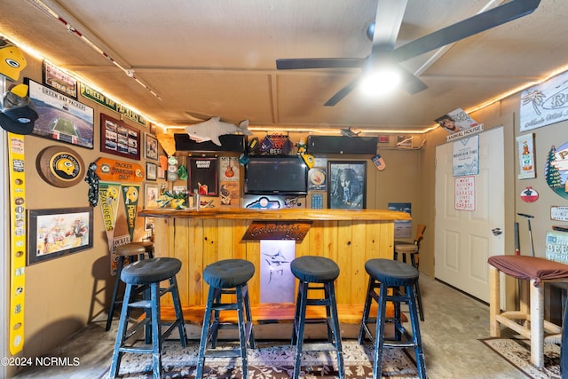 bar featuring a dry bar, ceiling fan, and concrete floors