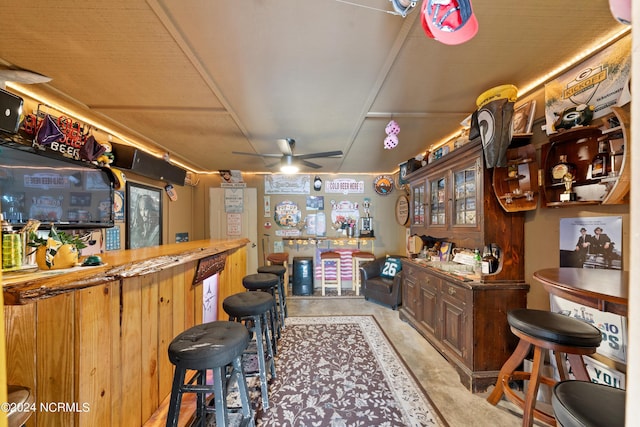 bar with a ceiling fan, concrete floors, and a bar