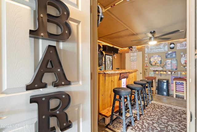 bar with concrete flooring, a dry bar, and a ceiling fan