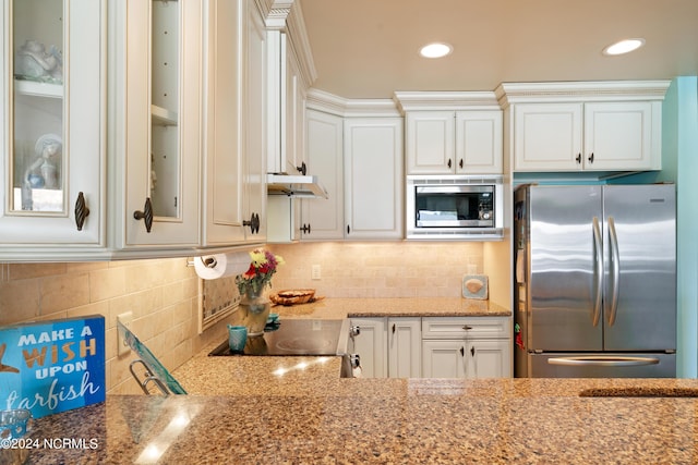 kitchen featuring stainless steel appliances, white cabinetry, glass insert cabinets, and light stone countertops