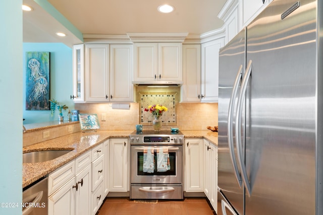 kitchen with appliances with stainless steel finishes, white cabinets, backsplash, and light stone counters