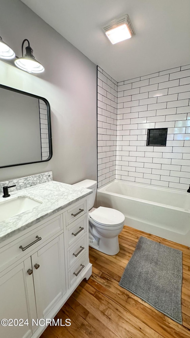 bathroom with toilet, shower / washtub combination, wood finished floors, and vanity