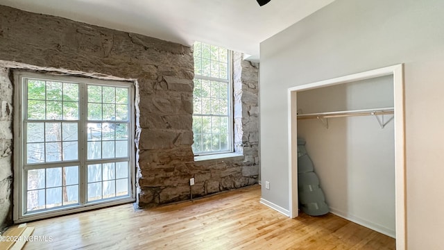 unfurnished bedroom featuring a closet, ceiling fan, multiple windows, and wood finished floors