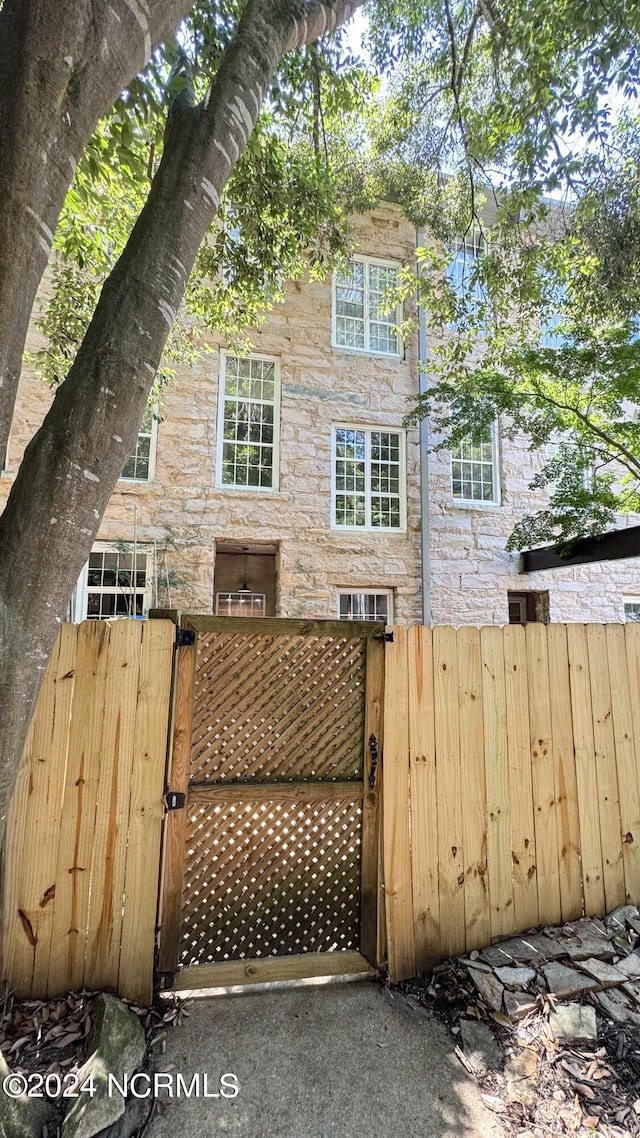 exterior space with stone siding, fence, and a gate