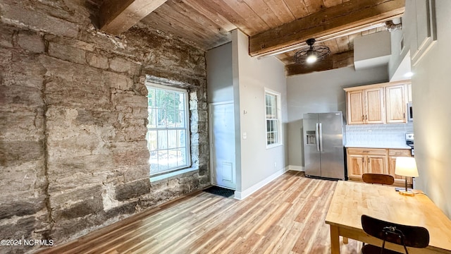 kitchen with light wood finished floors, stainless steel fridge with ice dispenser, beamed ceiling, light brown cabinetry, and backsplash