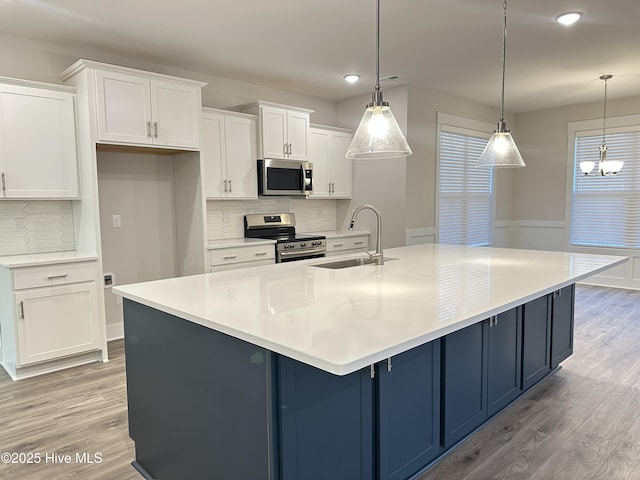 kitchen with appliances with stainless steel finishes, a spacious island, hanging light fixtures, and sink