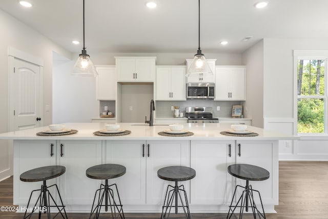 kitchen with a large island, a breakfast bar area, white cabinets, appliances with stainless steel finishes, and sink