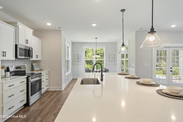 kitchen featuring stainless steel appliances, sink, white cabinetry, tasteful backsplash, and pendant lighting