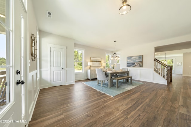 dining space featuring dark wood-type flooring and an inviting chandelier