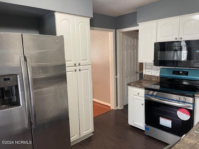 kitchen with white cabinetry, appliances with stainless steel finishes, dark wood-type flooring, and a textured ceiling