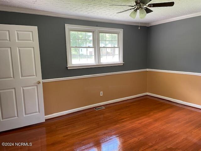 empty room with ceiling fan, crown molding, hardwood / wood-style floors, and a textured ceiling