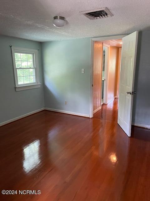 empty room with dark wood-type flooring and a textured ceiling