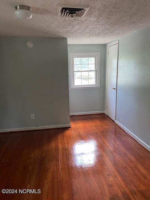 spare room featuring hardwood / wood-style flooring and a textured ceiling