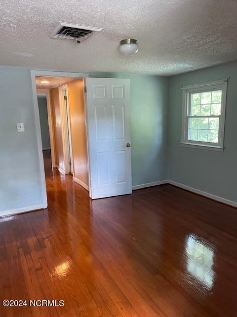 unfurnished bedroom featuring dark wood-type flooring and a textured ceiling