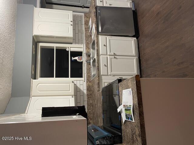 kitchen featuring white cabinetry and wood walls