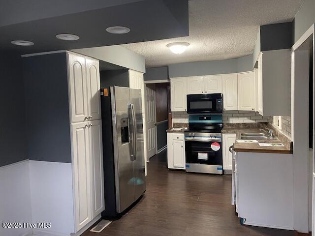 kitchen featuring sink, dark wood-type flooring, white cabinetry, stainless steel appliances, and decorative backsplash