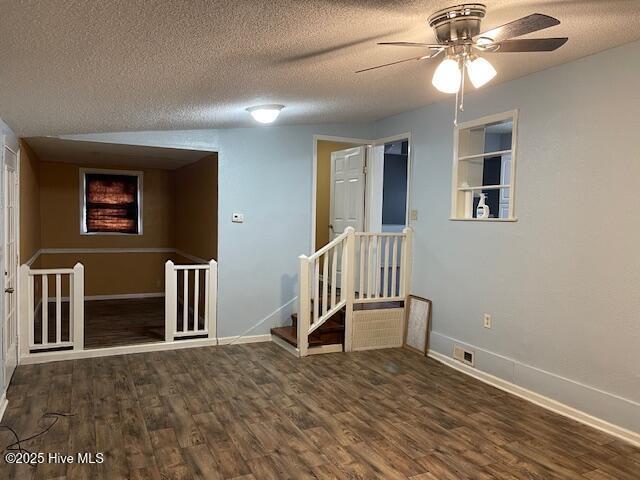 unfurnished room featuring ceiling fan, dark hardwood / wood-style floors, built in features, and a textured ceiling