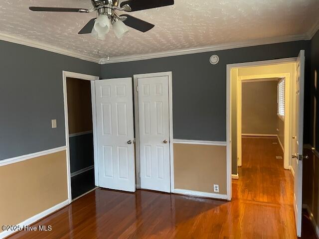 unfurnished bedroom featuring hardwood / wood-style flooring, ceiling fan, ornamental molding, and a textured ceiling