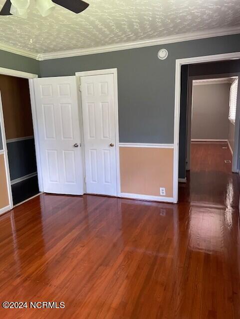 unfurnished bedroom featuring crown molding, dark wood-type flooring, and a textured ceiling