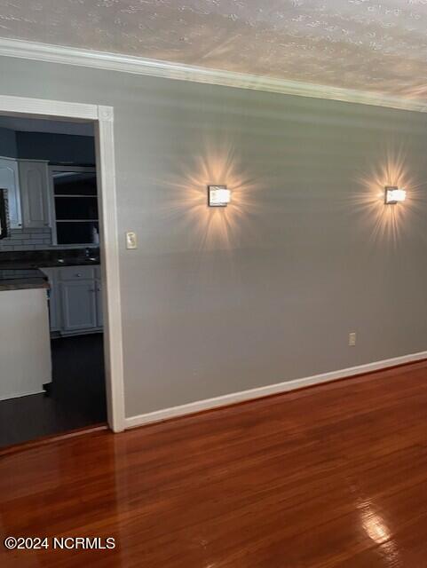 unfurnished room featuring crown molding, hardwood / wood-style flooring, and a textured ceiling